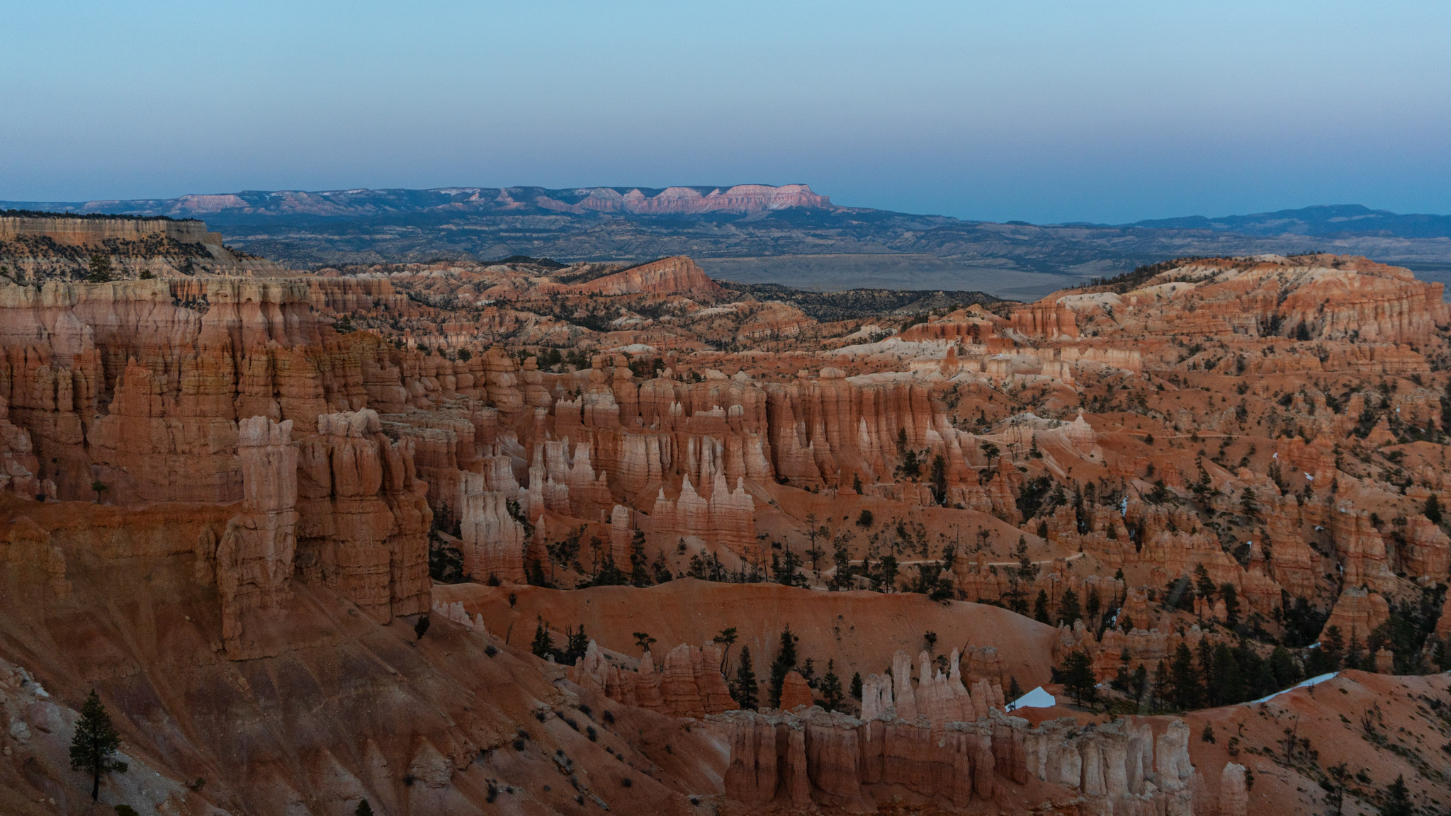 Orange stripey hoodos in the soft light just after sunset, the more distant landscape blue behind